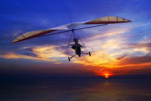 The motorized hang glider in the sunset above sea